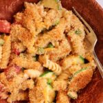 Closeup of mac and cheese with veggies in a dark brown shallow bowl.