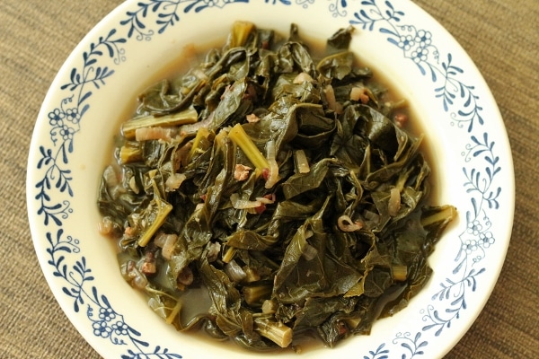 overhead view of braised collard greens in broth in a shallow white bowl