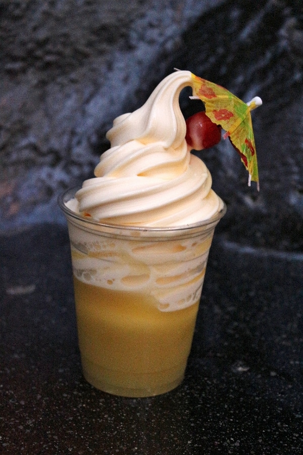 closeup of a clear plastic cup with pineapple juice and frozen dole whip over the top
