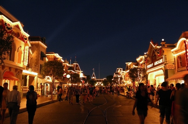 A group of people walking down Main Street U.S.A. at Disneyland at night