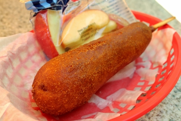 a closeup of a fried corn dog in a red plastic basket