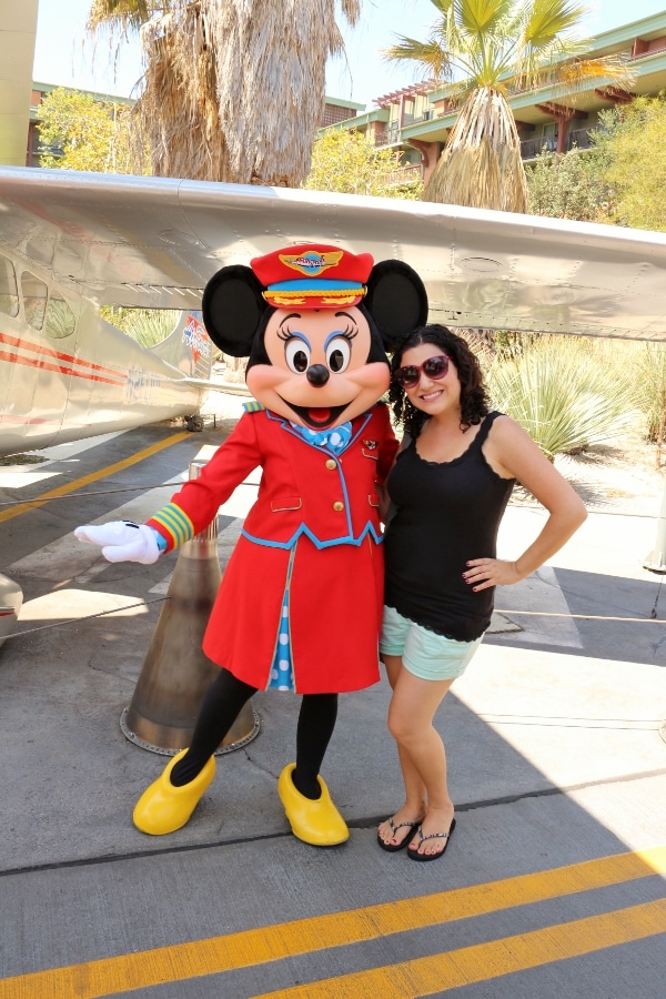 A woman posing with Minnie Mouse who is dressed like a flight attendant