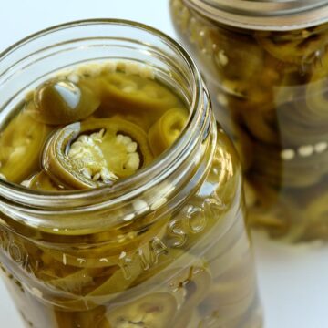 A close up view of 2 jars of pickled jalapeno peppers.