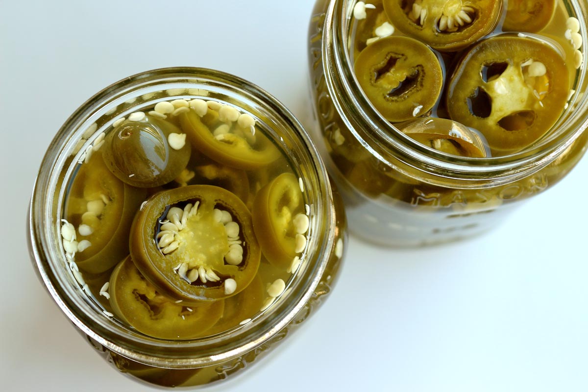 An overhead view of 2 jars of homemade pickled jalapenos.