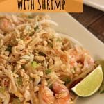 closeup of pad thai noodles with shrimp and lime wedges on a square plate