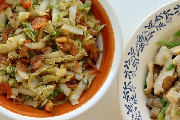 overhead view of two dishes of food including one with cabbage and dried shrimp