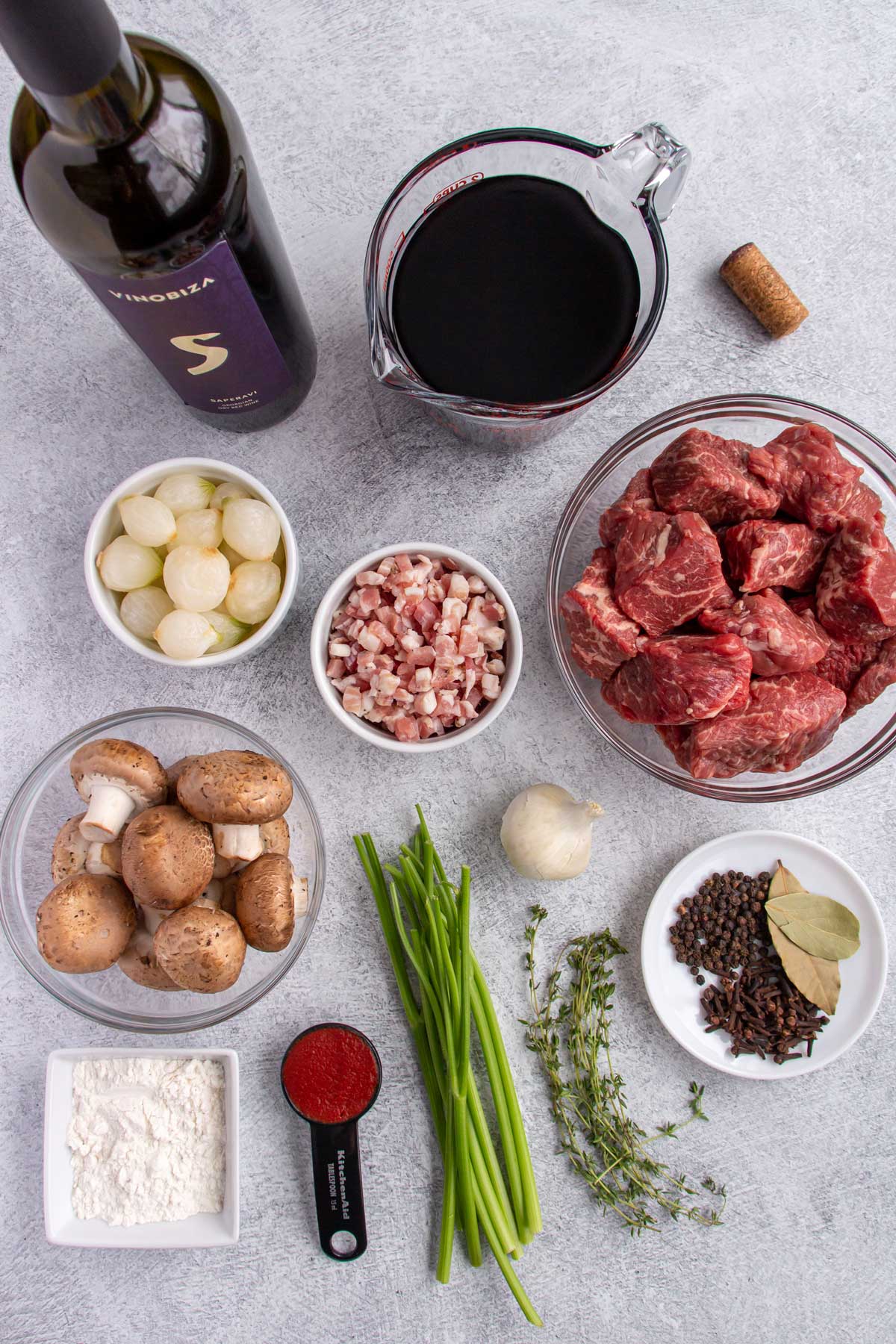 Ingredients for burgundy beef stew on a grey background.