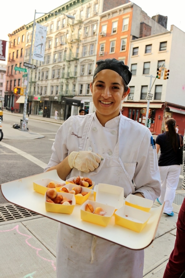 A person holding a white tray with yellow boxes of pastries