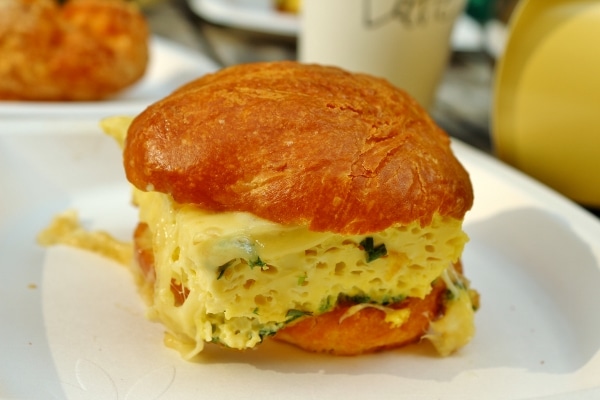 A close up of an egg sandwich on a white plate on a table