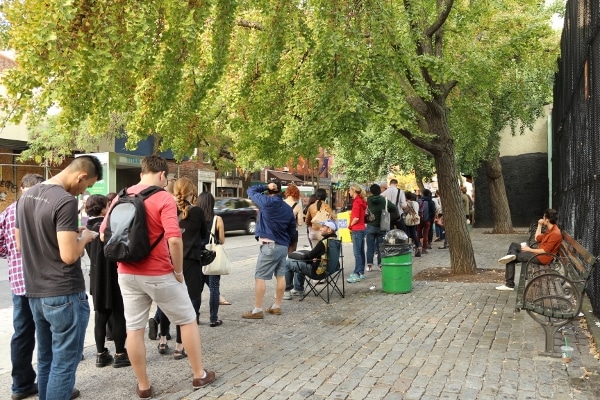 A group of people waiting in a long line on a sidewalk