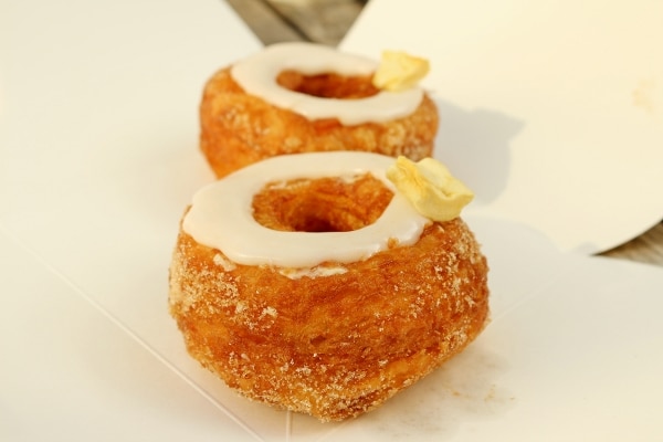 two Cronuts with a ring of white glaze and a piece of dried apple on top