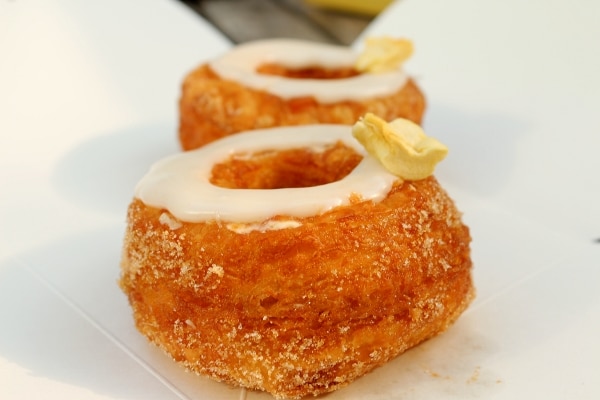 a closeup side view of a Cronut with a ring of white glaze on top