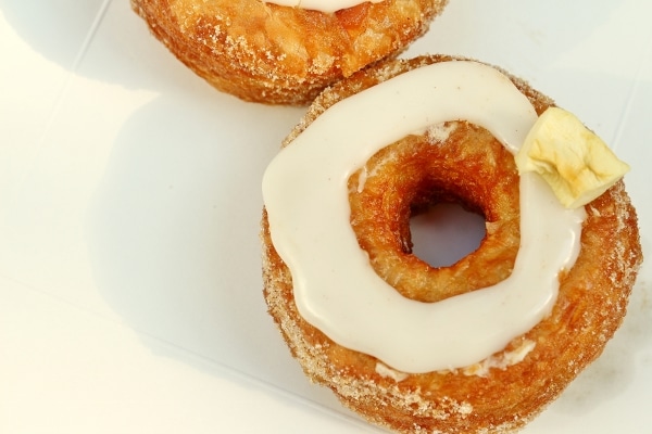 overhead closeup of a Cronut topped with a ring of white glaze and dried apple