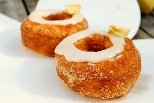 two doughnuts with a ring of glaze on top on a white surface
