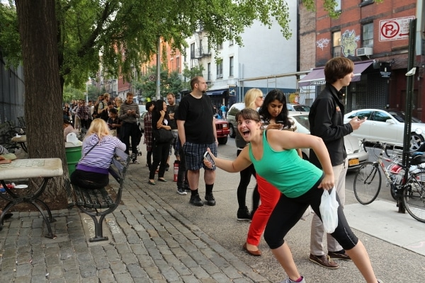 a very long line of people waiting on a sidewalk