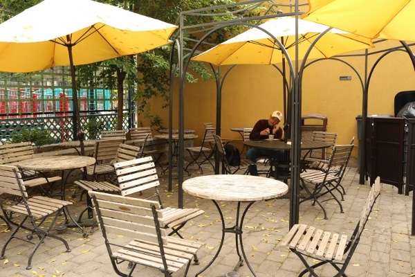 A group of tables and chairs outside with yellow umbrellas