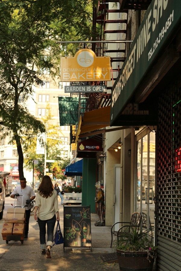 view down a city sidewalk with various shops and people walking