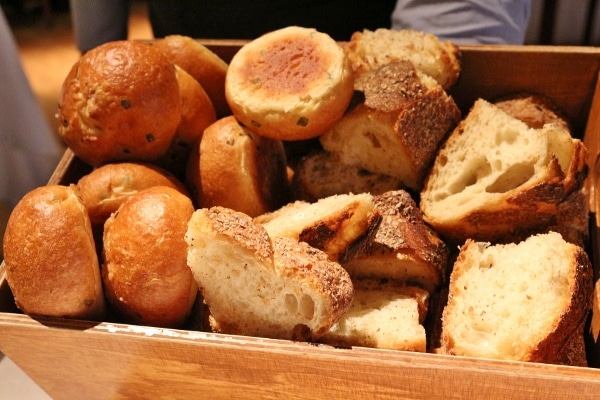 a closeup of a wooden box filled with a variety of bread slices and rolls