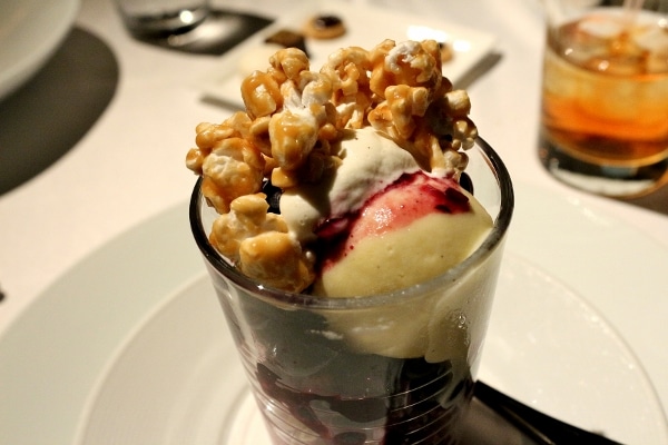 a glass filled with ice cream, berries, and caramel popcorn