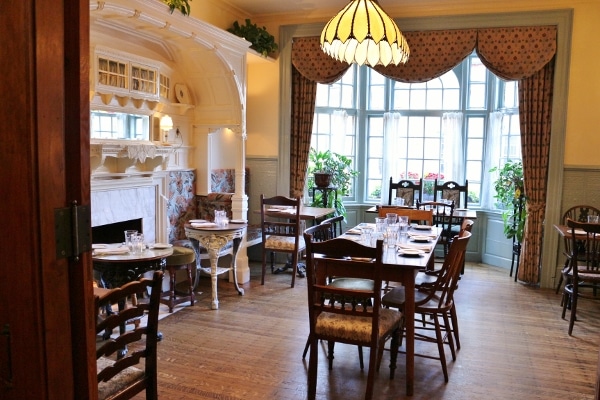 a cozy dining room with wooden tables and chairs, warm lighting, and quaint decor