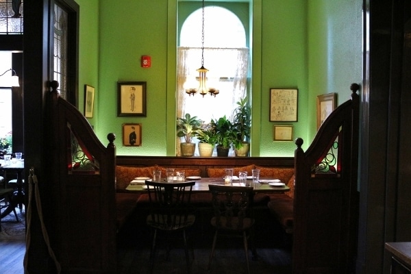 a table with booth seating in front of a bright green wall with a window