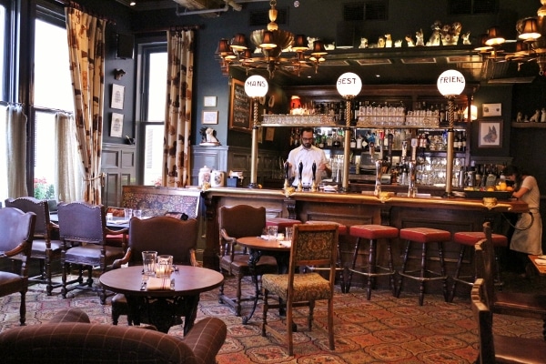 wide view of a bar with dark walls and comfy chairs