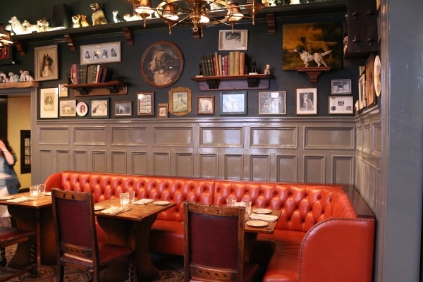 a long red tufted booth with photos of dogs hanging overhead