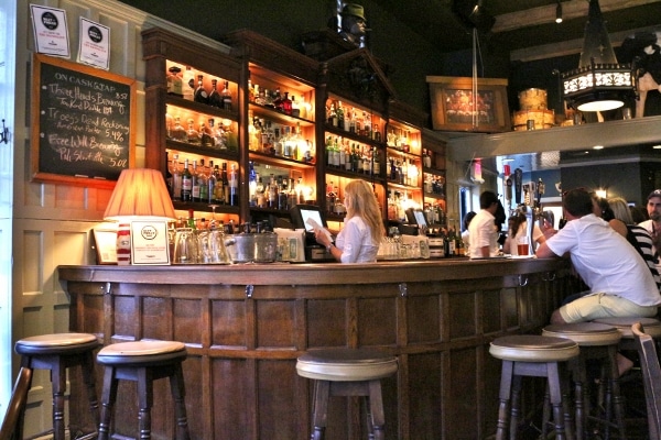 a wooden restaurant bar with people sitting around it