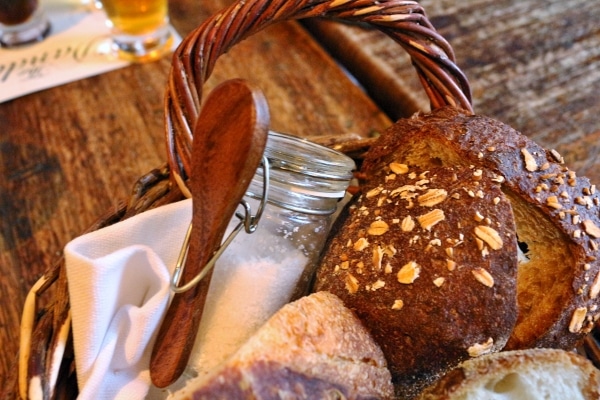 closeup of a bread basket with a jar of salt and a wooden spoon