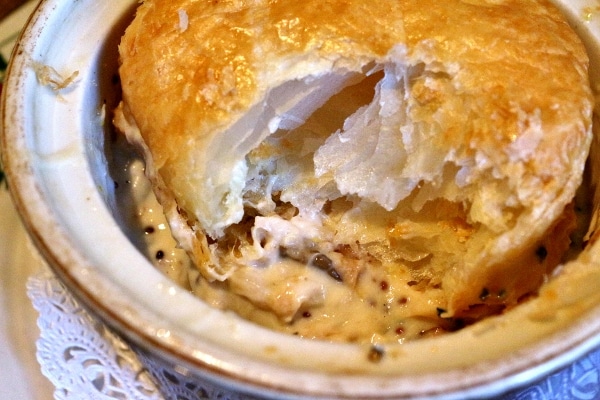 a closeup of a half eaten pot pie with a creamy filling and flaky topping