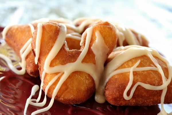 A closeup of a Mickey Mouse shaped fried beignet drizzled with white glaze