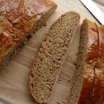 overhead view of sliced brown bread on a wooden board