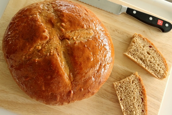 overhead view of a round loaf of honey glazed bread on a wooden board