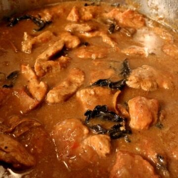 a round metal pan filled with braised meat in a light brown sauce