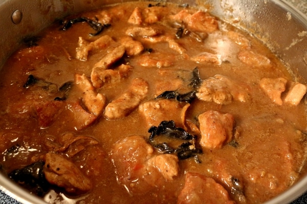 a round metal pan filled with braised meat in a light brown sauce