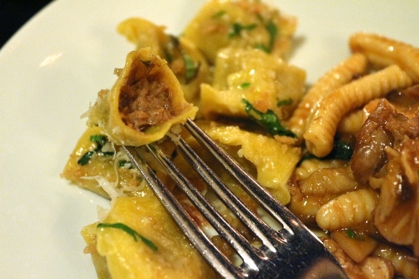 a closeup of a forkful of stuffed pasta bitten to show the meat filling