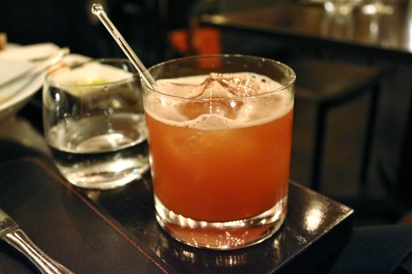 a pink cocktail in a short glass on a black surface