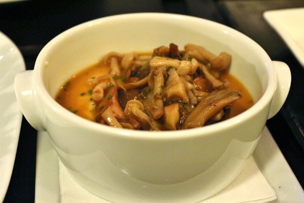 a closeup of a white bowl filled with cooked wild mushrooms