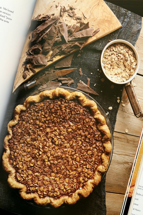 overhead view of a pie with chopped chocolate and a cup of dry oats beside it