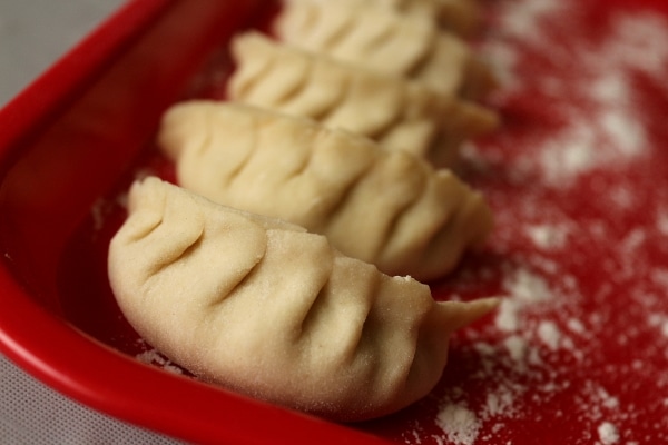 closeup of pleated Asian style dumplings on a red tray