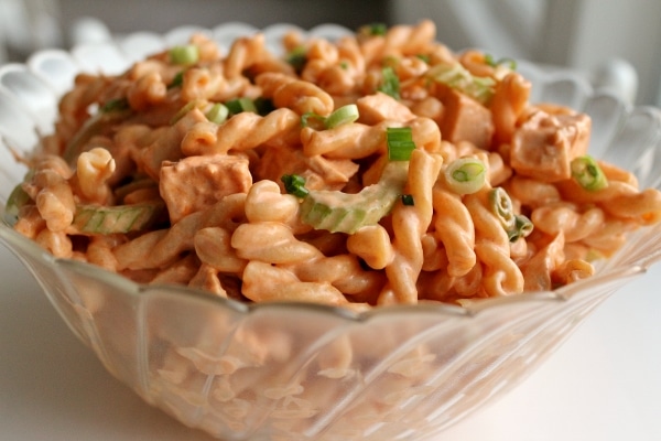 buffalo chicken pasta salad with celery and scallions in a large glass bowl