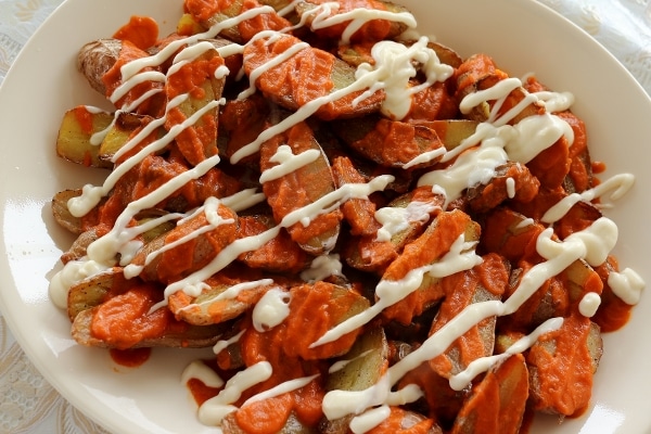 a platter of halved small potatoes topped with red and white sauces