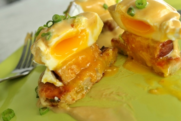 closeup of a cross section of an eggs benedict showing off the runny egg yolk