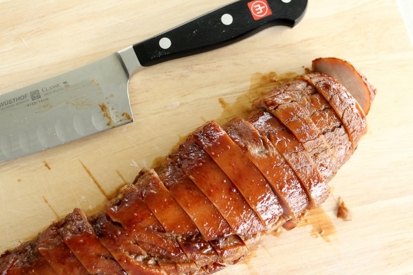 a sliced char siu style roasted pork tenderloin on a wooden board