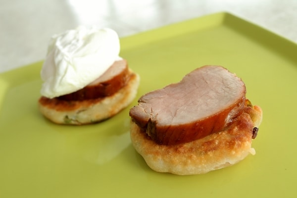 assembling eggs benedict with scallion pancakes and sliced roasted pork