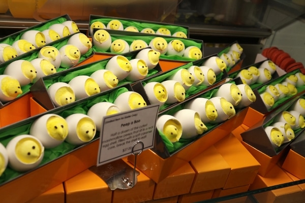 a closeup of rows of yellow marshmallow peeps peeking out of white eggshells