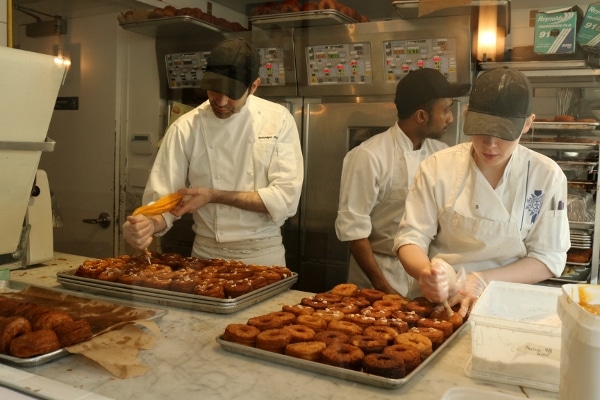 a group of people working in a bakery to prepare desserts