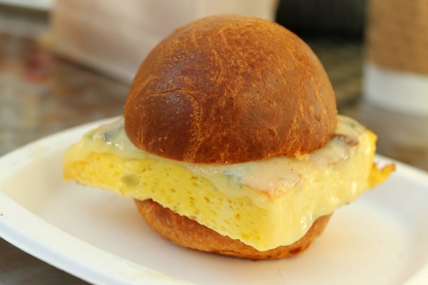 closeup of a breakfast sandwich on a golden bun with a square piece of egg inside