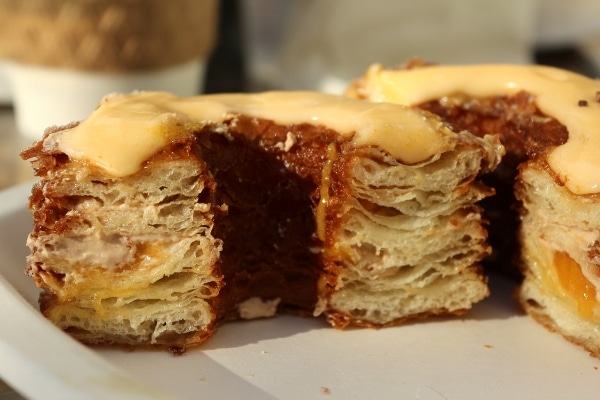 A closeup of a cross section of a flaky Cronut with layers of pasty