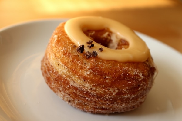 side view of a fried Cronut topped with a ring of orange sauce
